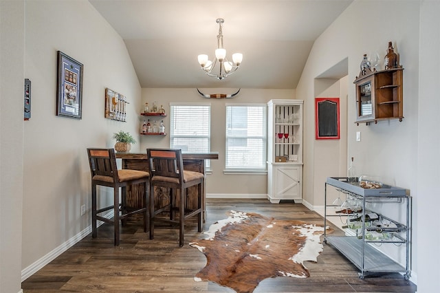 dining area with a notable chandelier, lofted ceiling, and dark hardwood / wood-style floors