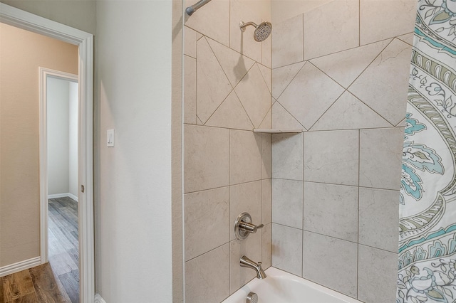 bathroom with wood-type flooring and tiled shower / bath