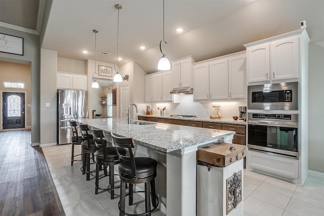 kitchen with a kitchen island with sink, hanging light fixtures, stainless steel appliances, and white cabinets