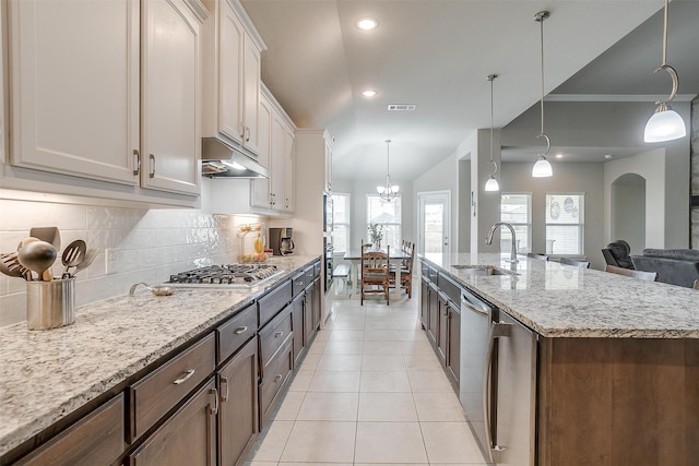 kitchen with a center island with sink, light tile patterned floors, white cabinetry, decorative light fixtures, and sink