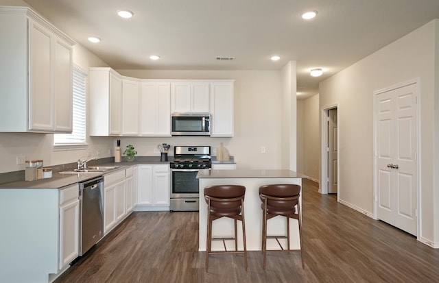 kitchen featuring dark hardwood / wood-style floors, a center island, stainless steel appliances, and white cabinetry