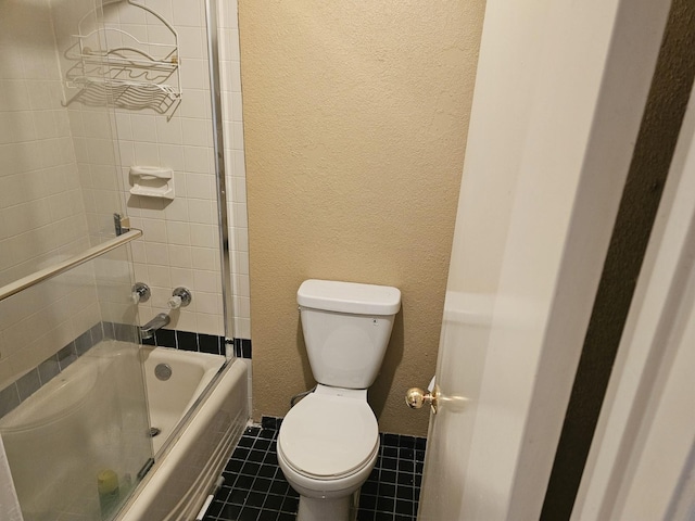 bathroom with tile patterned flooring, combined bath / shower with glass door, and toilet