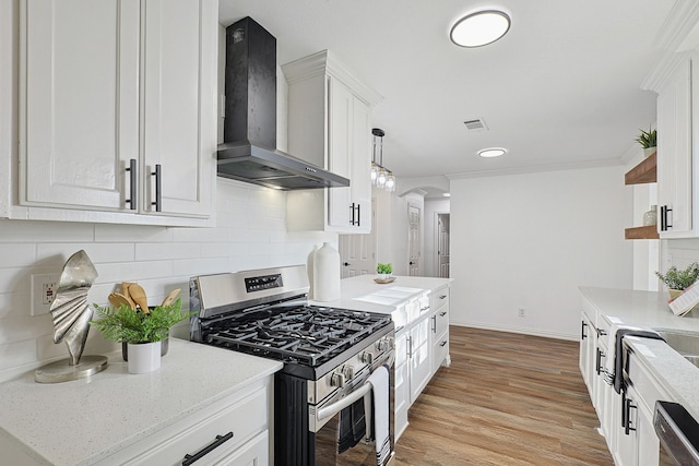 kitchen featuring pendant lighting, white cabinets, wall chimney exhaust hood, decorative backsplash, and stainless steel range with gas stovetop