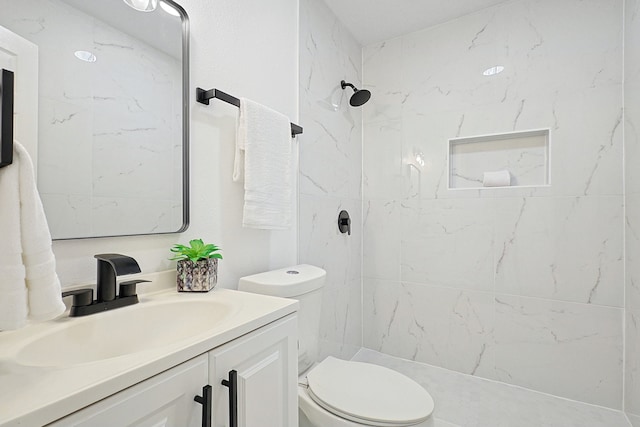 bathroom with vanity, toilet, and tiled shower