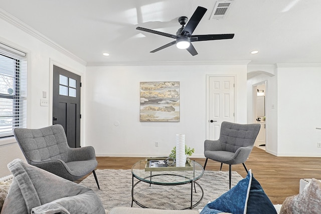 living room with ceiling fan, light wood-type flooring, and crown molding