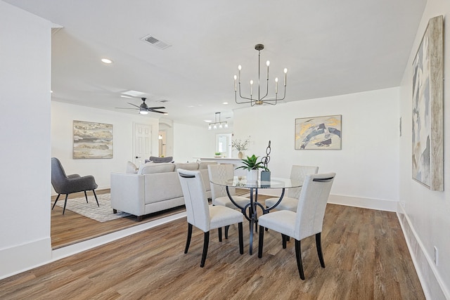 dining space with wood-type flooring and ceiling fan with notable chandelier