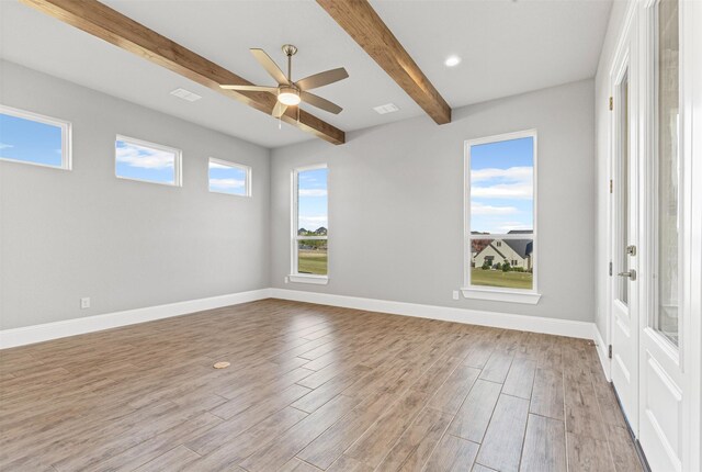 unfurnished room featuring ceiling fan, light hardwood / wood-style floors, and beam ceiling