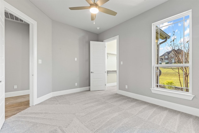 carpeted bedroom featuring multiple windows, ceiling fan, a closet, and a walk in closet