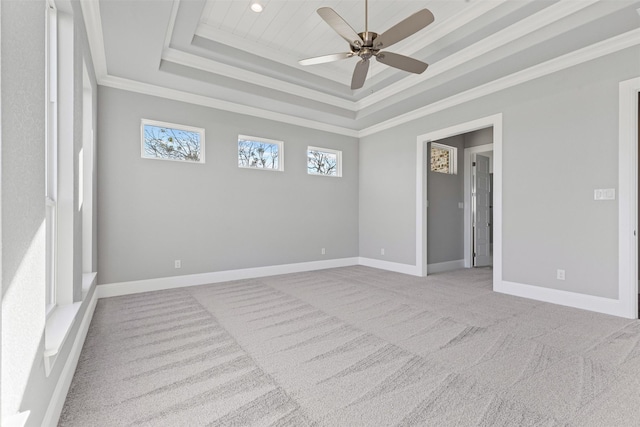 empty room featuring a raised ceiling, crown molding, ceiling fan, and light colored carpet