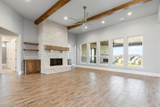 unfurnished living room featuring a towering ceiling, a fireplace, beamed ceiling, and light wood-type flooring