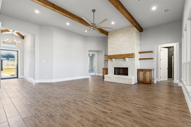 unfurnished living room with high vaulted ceiling, ceiling fan with notable chandelier, a stone fireplace, beamed ceiling, and dark hardwood / wood-style flooring