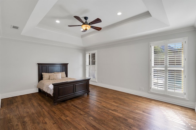 bedroom with ornamental molding, dark hardwood / wood-style floors, a tray ceiling, and ceiling fan