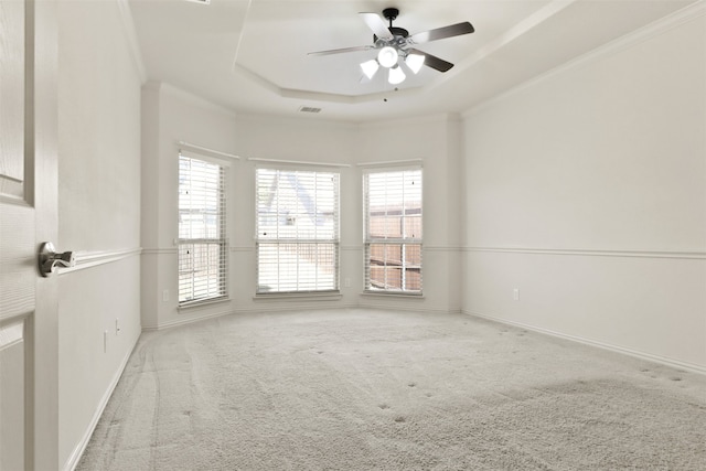 carpeted spare room with crown molding, a tray ceiling, and ceiling fan