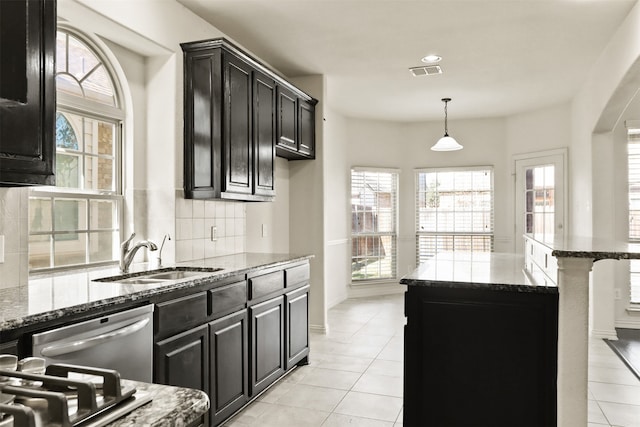 kitchen with a center island, sink, dark stone counters, and pendant lighting