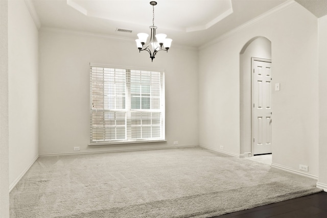 carpeted empty room with a notable chandelier, ornamental molding, and a raised ceiling