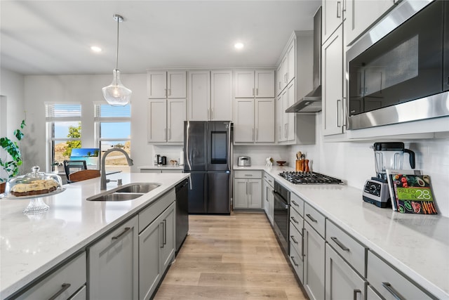 kitchen with light hardwood / wood-style flooring, gray cabinetry, sink, pendant lighting, and appliances with stainless steel finishes