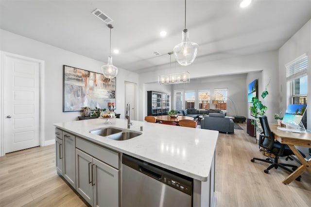 kitchen with light hardwood / wood-style flooring, a center island with sink, sink, decorative light fixtures, and stainless steel dishwasher