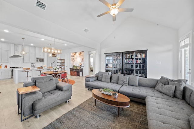 living room featuring light hardwood / wood-style flooring, high vaulted ceiling, and ceiling fan