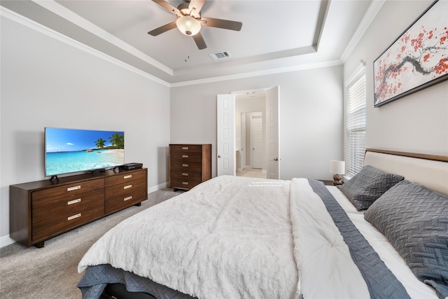 bedroom featuring ceiling fan, crown molding, a tray ceiling, and light colored carpet