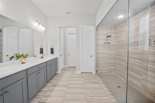 bathroom with vanity, tiled shower, and tile patterned flooring