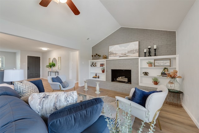 living room with vaulted ceiling, a brick fireplace, light wood-type flooring, and ceiling fan