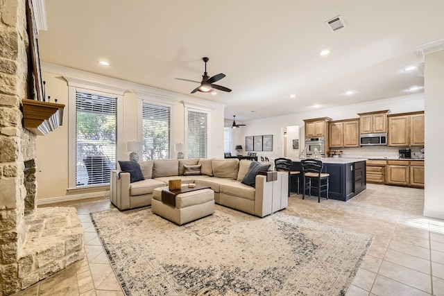 living room with crown molding, light tile patterned floors, and ceiling fan