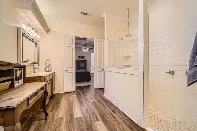 bathroom featuring ceiling fan, tiled shower, vanity, hardwood / wood-style flooring, and ornamental molding