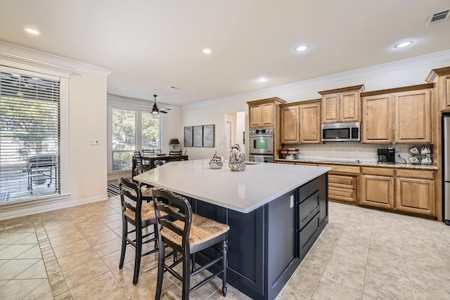 kitchen with visible vents, decorative backsplash, brown cabinets, a kitchen island, and appliances with stainless steel finishes