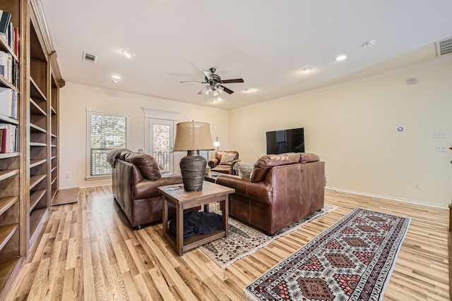 living room with light wood-type flooring, a ceiling fan, visible vents, and crown molding
