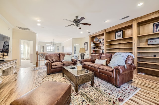 living room with light hardwood / wood-style floors, ornamental molding, and ceiling fan