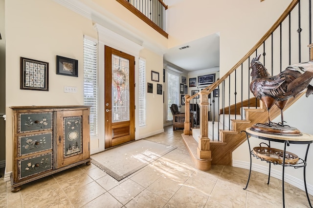 entrance foyer featuring a towering ceiling and ornamental molding