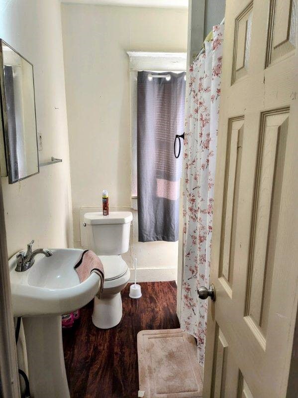 bathroom featuring toilet, wood-type flooring, and walk in shower