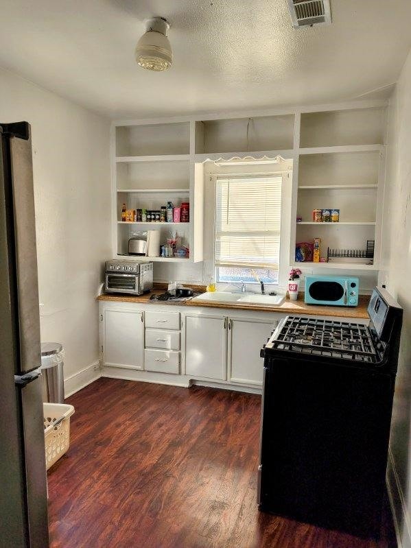 kitchen featuring stainless steel fridge, black electric range, white cabinets, a textured ceiling, and dark hardwood / wood-style flooring