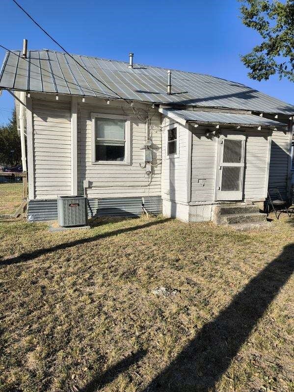 back of house with cooling unit and a yard