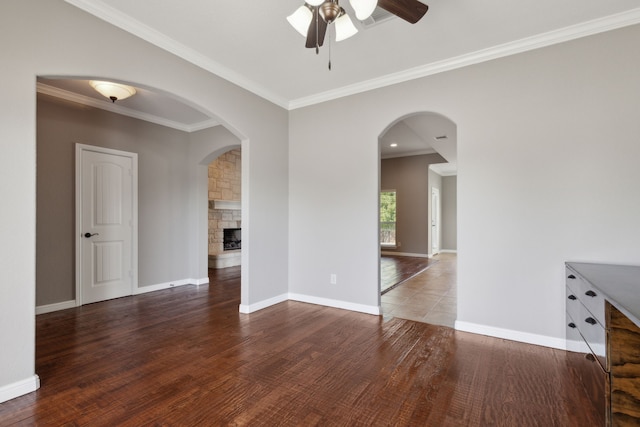 interior space featuring ceiling fan, a fireplace, ornamental molding, and dark hardwood / wood-style floors