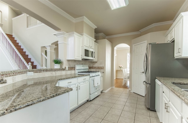 kitchen featuring white cabinetry, light stone countertops, light tile patterned floors, and white appliances