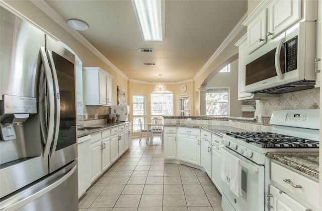 kitchen featuring backsplash, crown molding, light tile patterned floors, white cabinetry, and white appliances