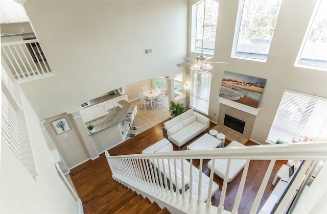 staircase featuring a towering ceiling, hardwood / wood-style flooring, and ceiling fan