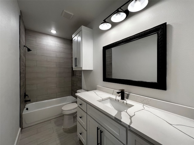 full bathroom with tiled shower / bath, vanity, and toilet