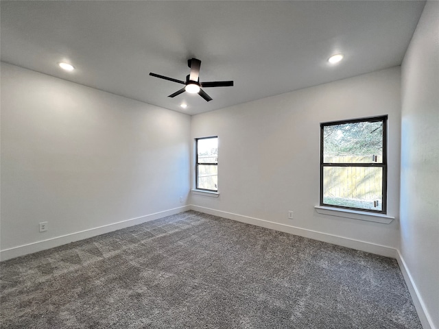 unfurnished room with dark carpet and ceiling fan