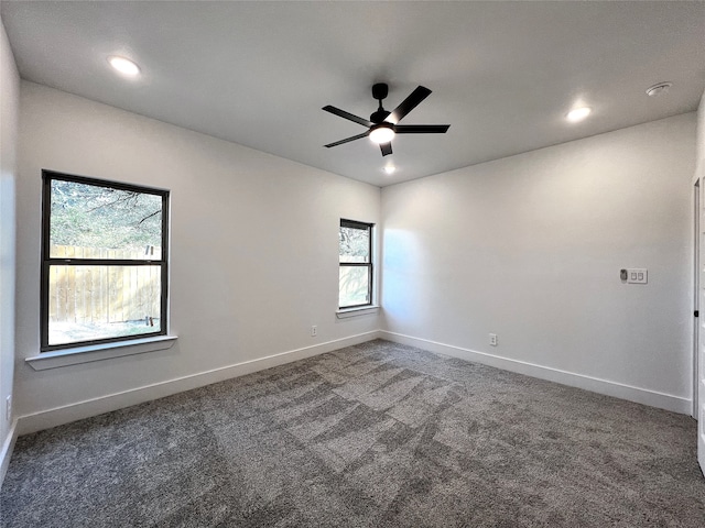 spare room with dark carpet and ceiling fan