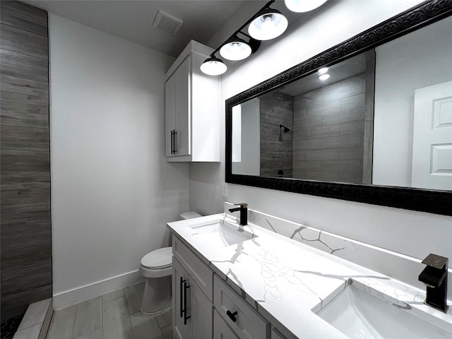 bathroom featuring vanity, toilet, and a tile shower