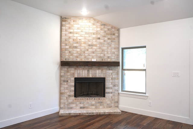 unfurnished living room with dark wood-type flooring, vaulted ceiling, and a brick fireplace