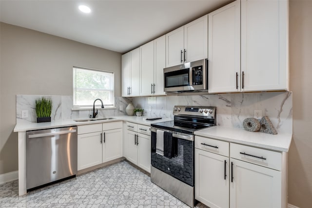 kitchen with white cabinetry, stainless steel appliances, tasteful backsplash, and sink