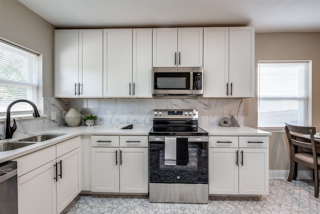 kitchen featuring backsplash, sink, appliances with stainless steel finishes, and white cabinetry