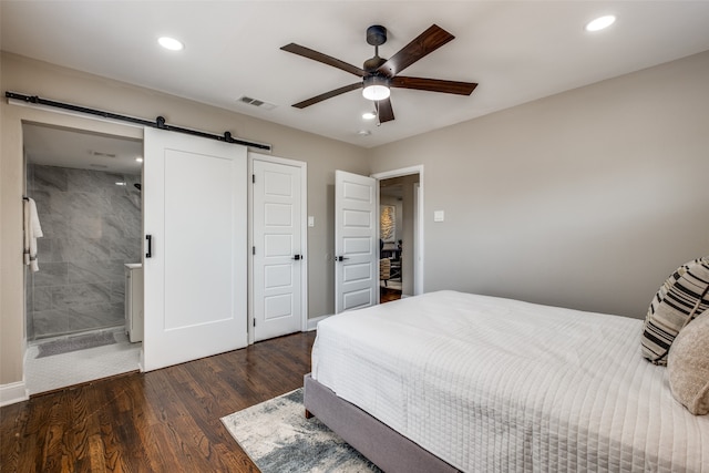 bedroom with connected bathroom, ceiling fan, dark wood-type flooring, and a barn door