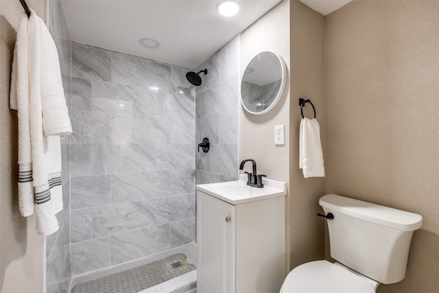 bathroom featuring vanity, toilet, and a tile shower