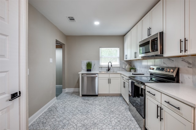 kitchen with backsplash, stainless steel appliances, sink, and white cabinets