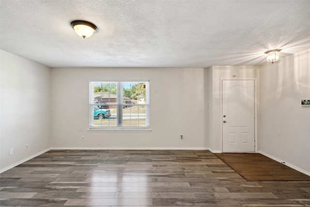 unfurnished room with a textured ceiling and dark hardwood / wood-style flooring