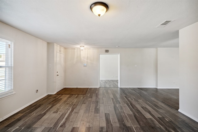 unfurnished room featuring a textured ceiling and dark hardwood / wood-style floors